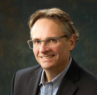 A person wearing glasses and a suitAI-generated content may be incorrect.