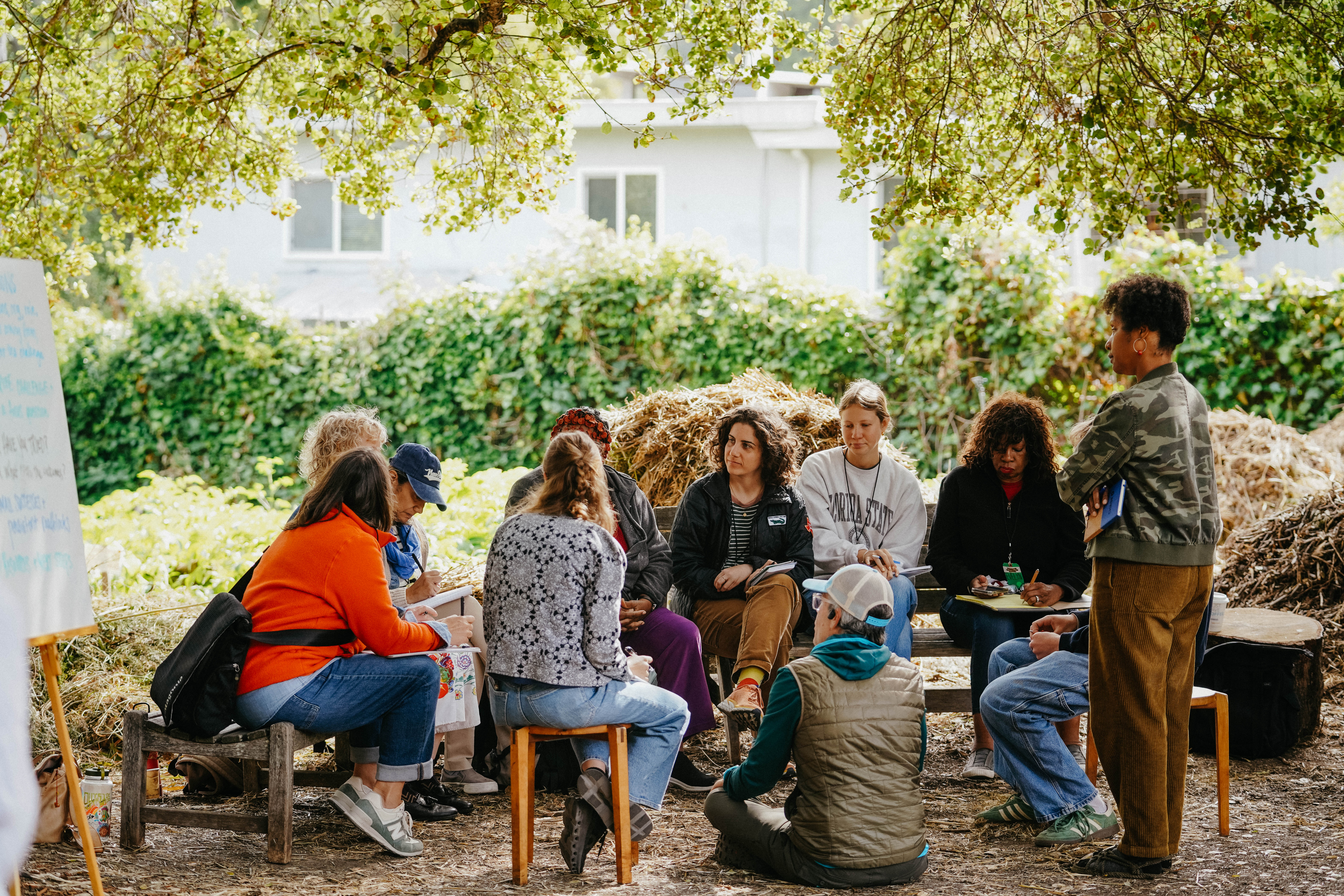 Educators sitting in a circle outside receiving instruction