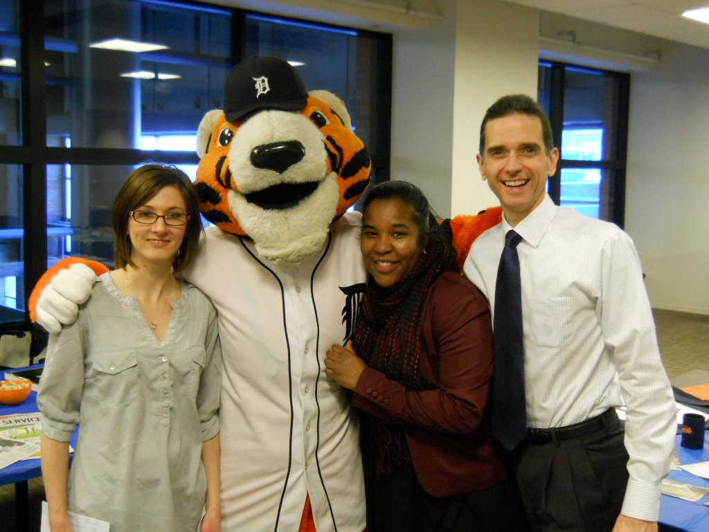 Bodman Thinks Spring (Training) Detroit is a sports-crazy town and Bodman PLC is at the heart of it all. The firm’s headquarters office is located inside Ford Field, home of the Detroit Lions, and directly across the street from Comerica Park, home of the Detroit Tigers. The Firm often schedules events to coincide with local sports milestones, and has for several years celebrated the opening of major league baseball spring training with baseball-theme snacks and a display of baseball memorabilia donated for the day by firm personnel. This year’s celebration was highlighted by a visit from PAWS, the Detroit Tigers’ mascot, who is pictured above with Bodman marketing staff members (from left to right) Kristyn Kelley, Akilah Paramore, and Tony Allegrina.