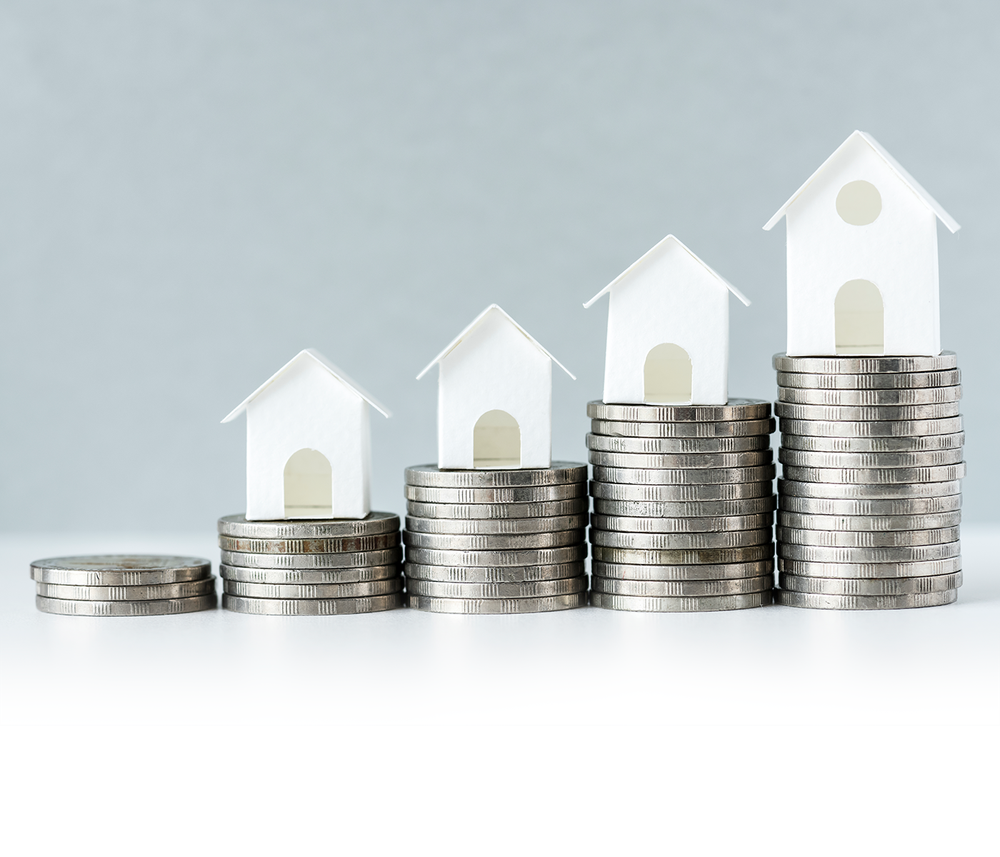 photo of stacks of coins in front of model houses