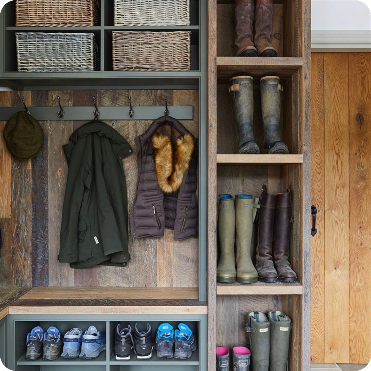 Image of coats and boots organized in a wooden mudroom with natural light coming in