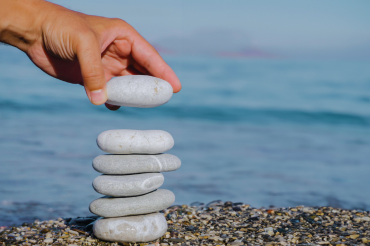 hand stacking a stone on top of five others on the beach