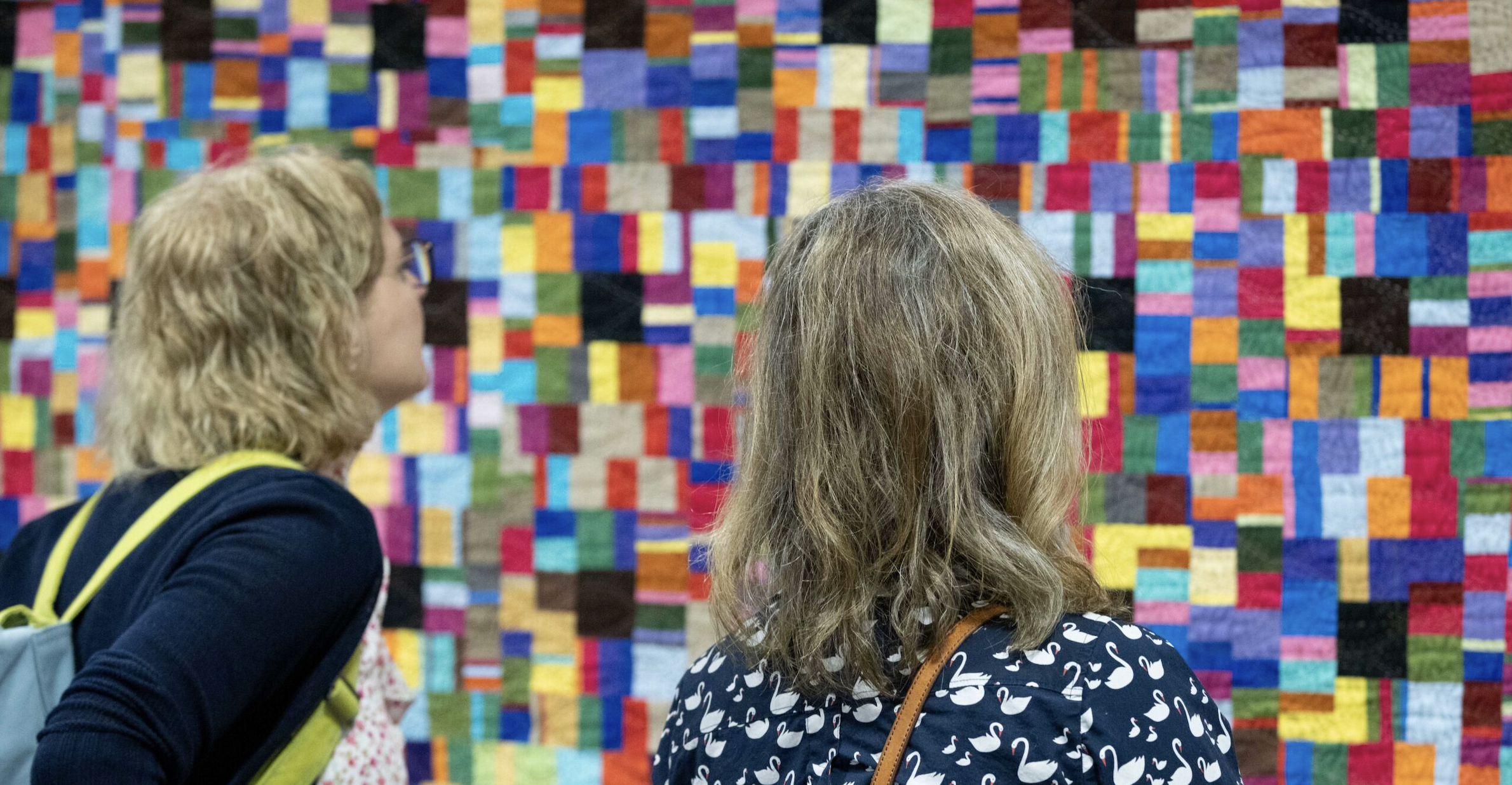 Two people viewing quilts