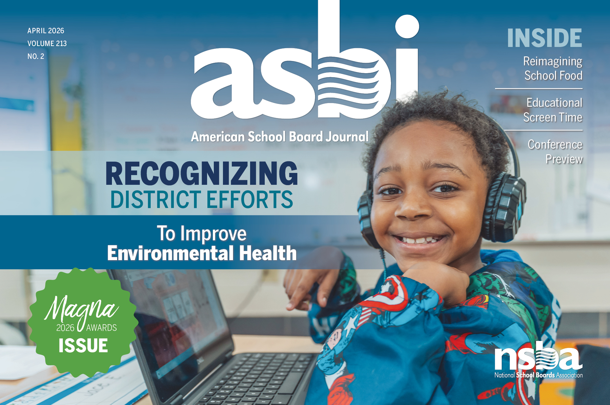 A student smiles at the camera while working on a laptop