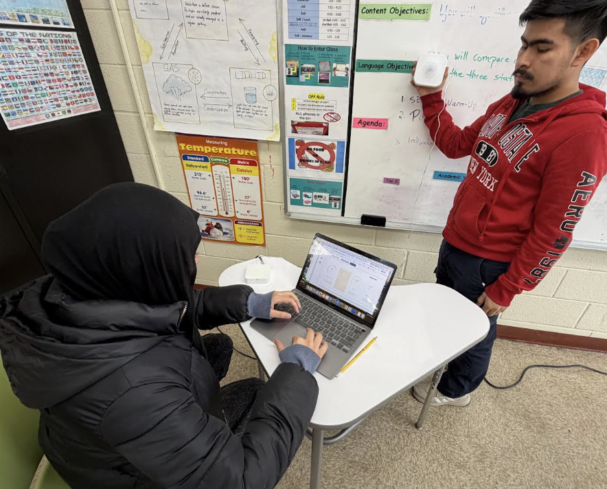 A student holds an indoor air quality monitor to collect data in his classroom. 