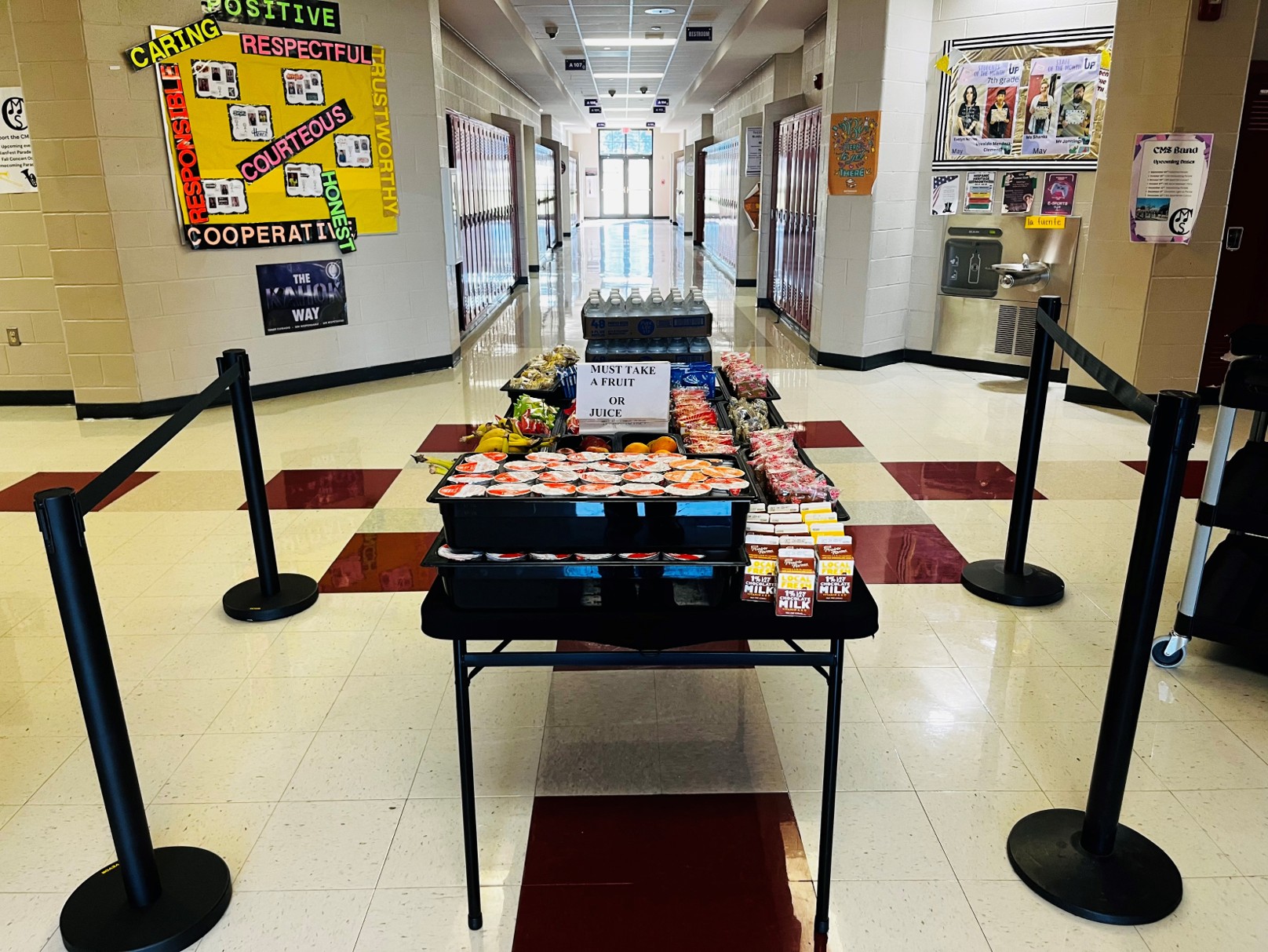 A cart in a school hallway is stocked with breakfast foods for students. 