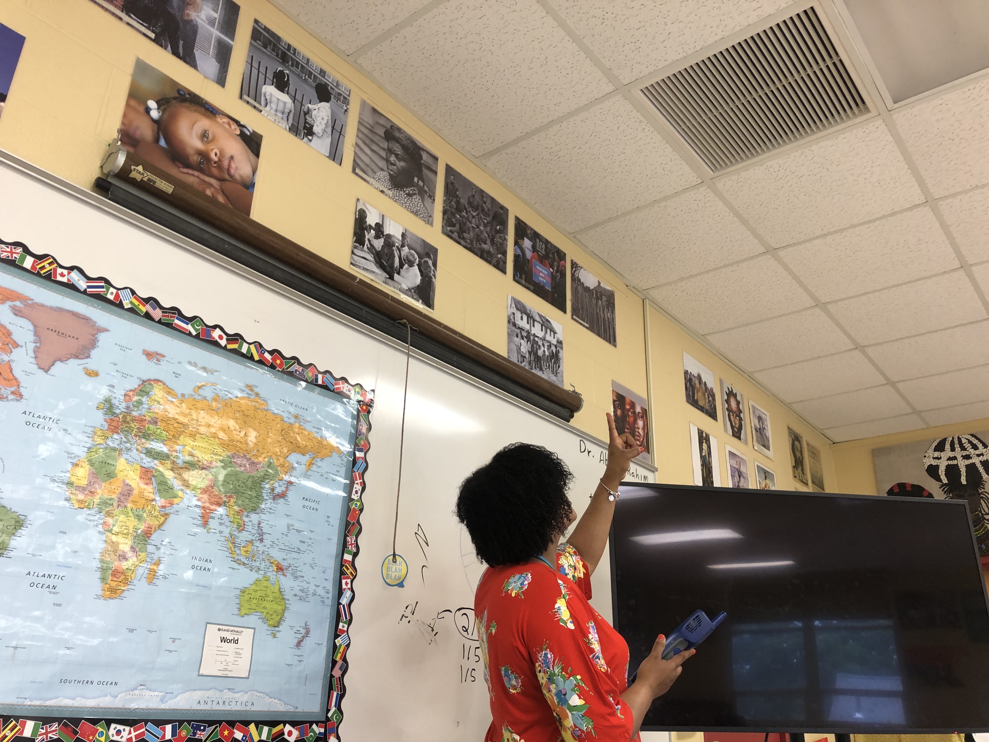 A classroom teacher points to the air vent in the ceiling