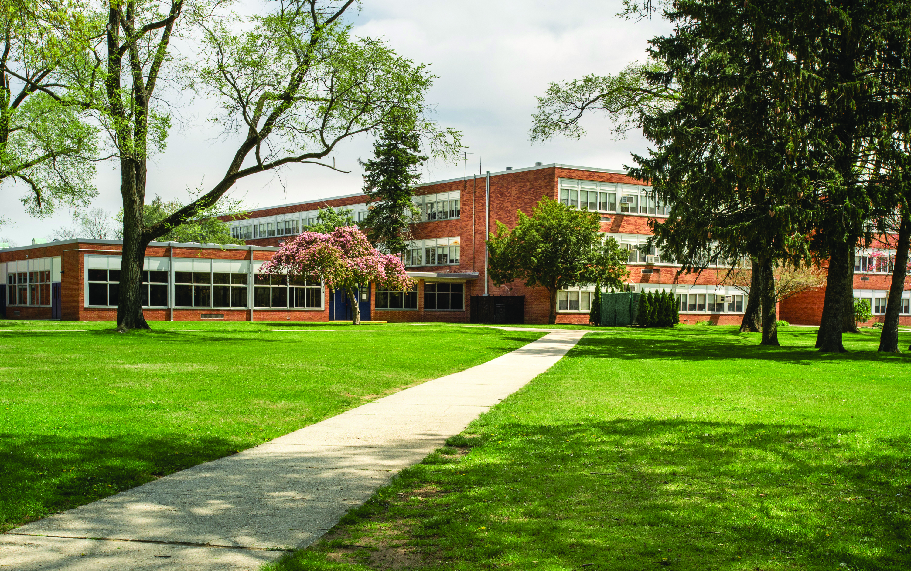 School building with green grass and trees in front of it