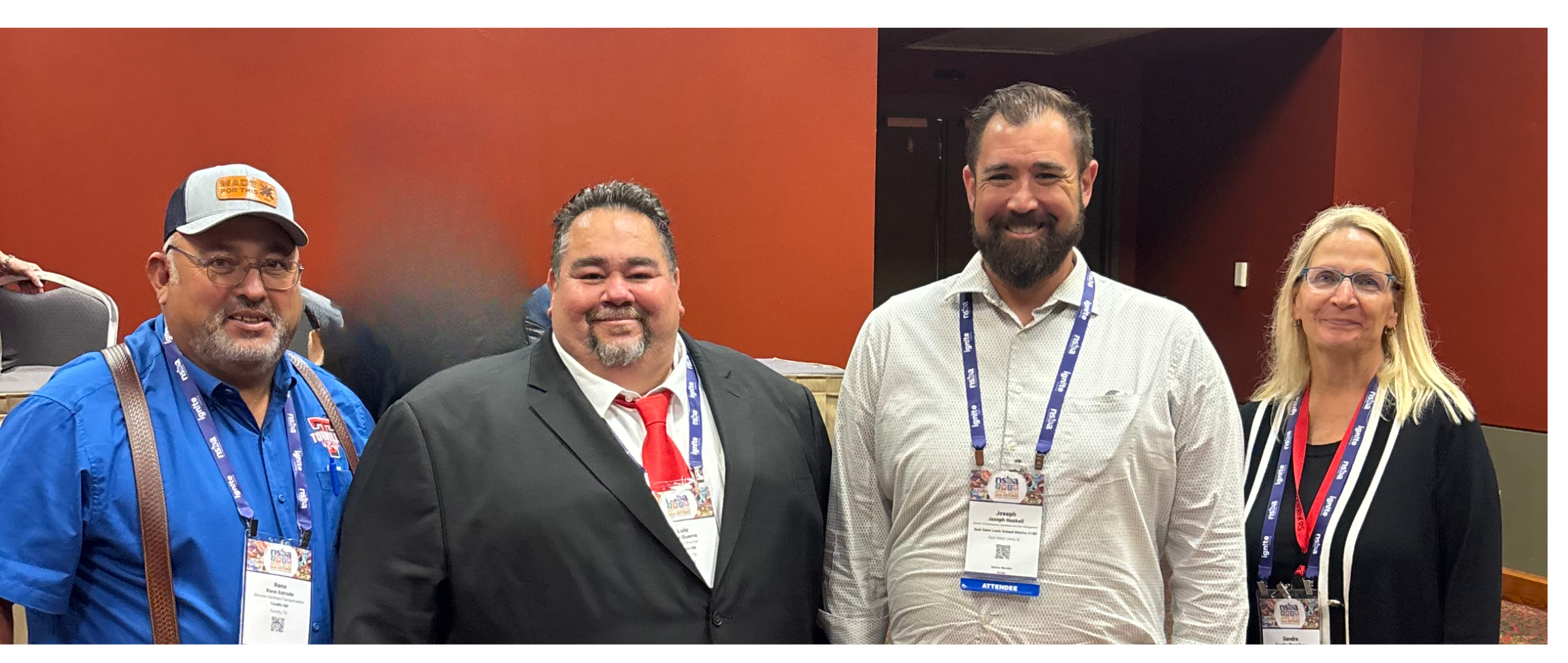 Three men and one woman pose together after making a presentation at a conference. 