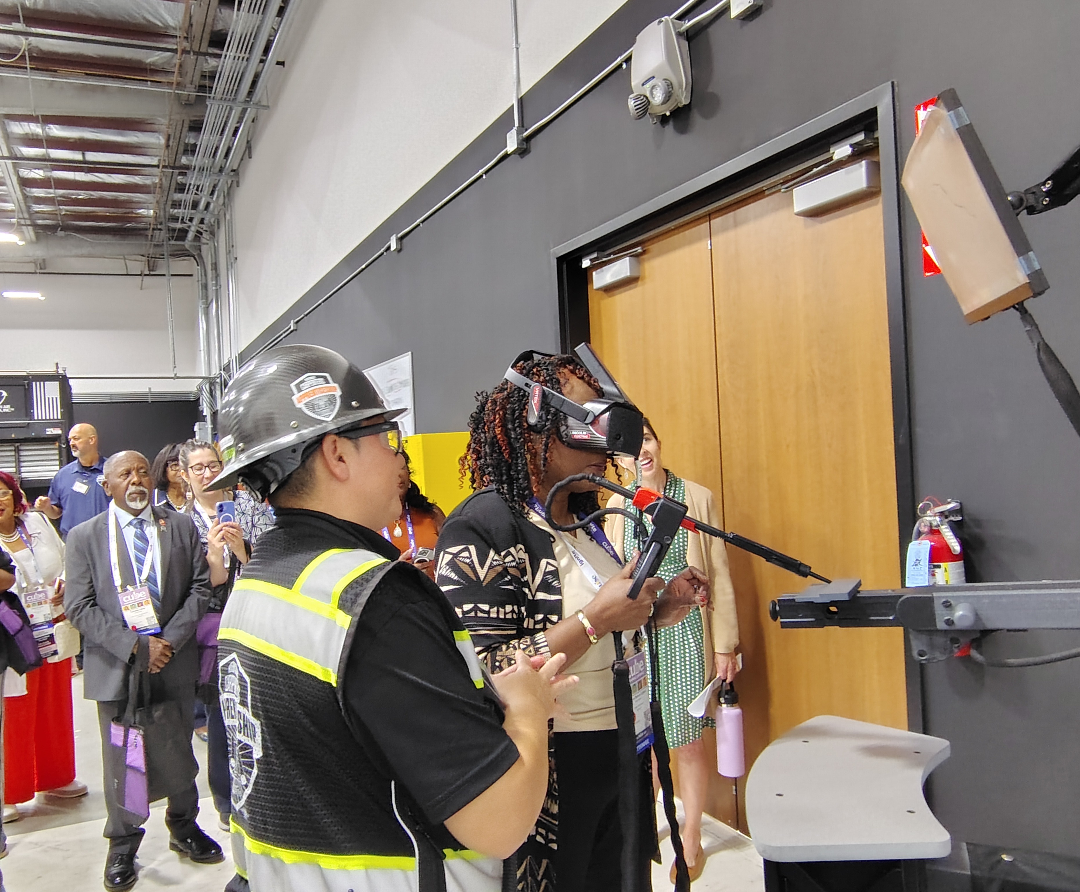 A carpentry student shows a class visitor how to use a tool. 