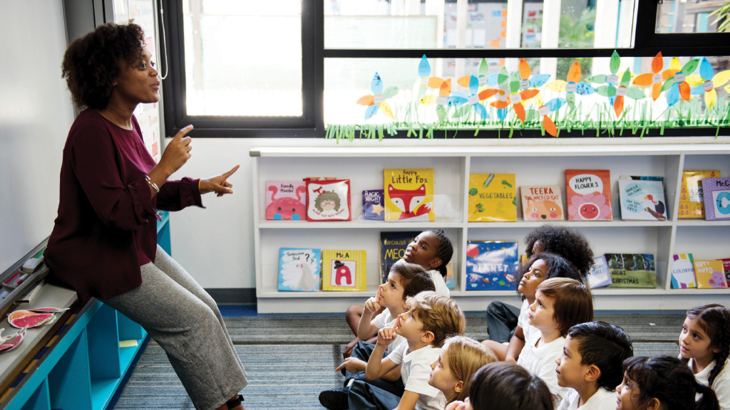 A classroom teacher talks to a group of seated students
