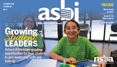 Two students sitting at a table smile at the camera