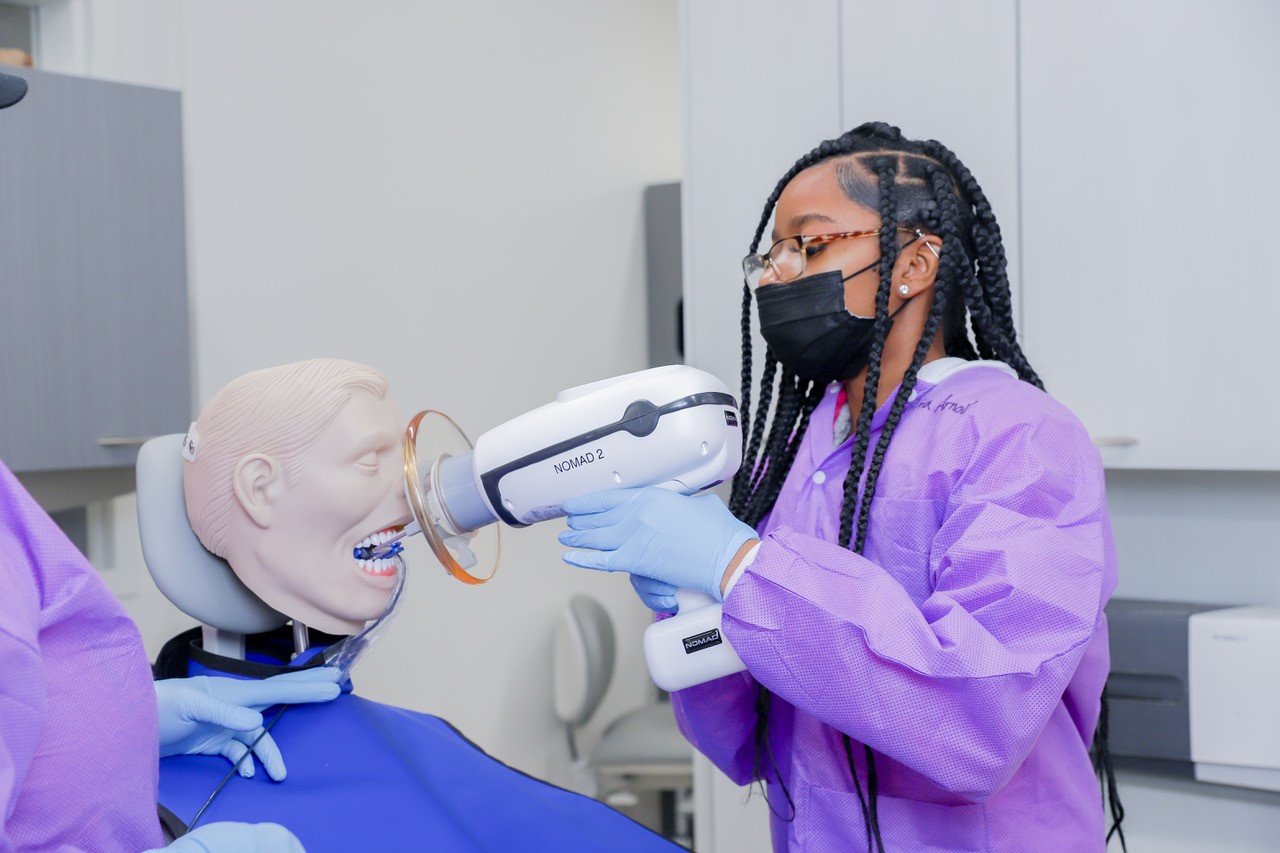 A high school student performs a dental exam on a classroom mannequin.