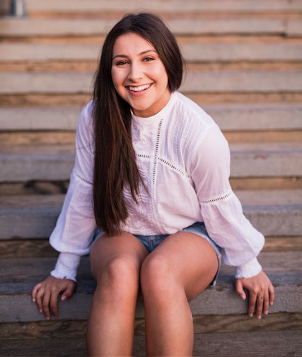 A person sitting on stairs smilingDescription automatically generated