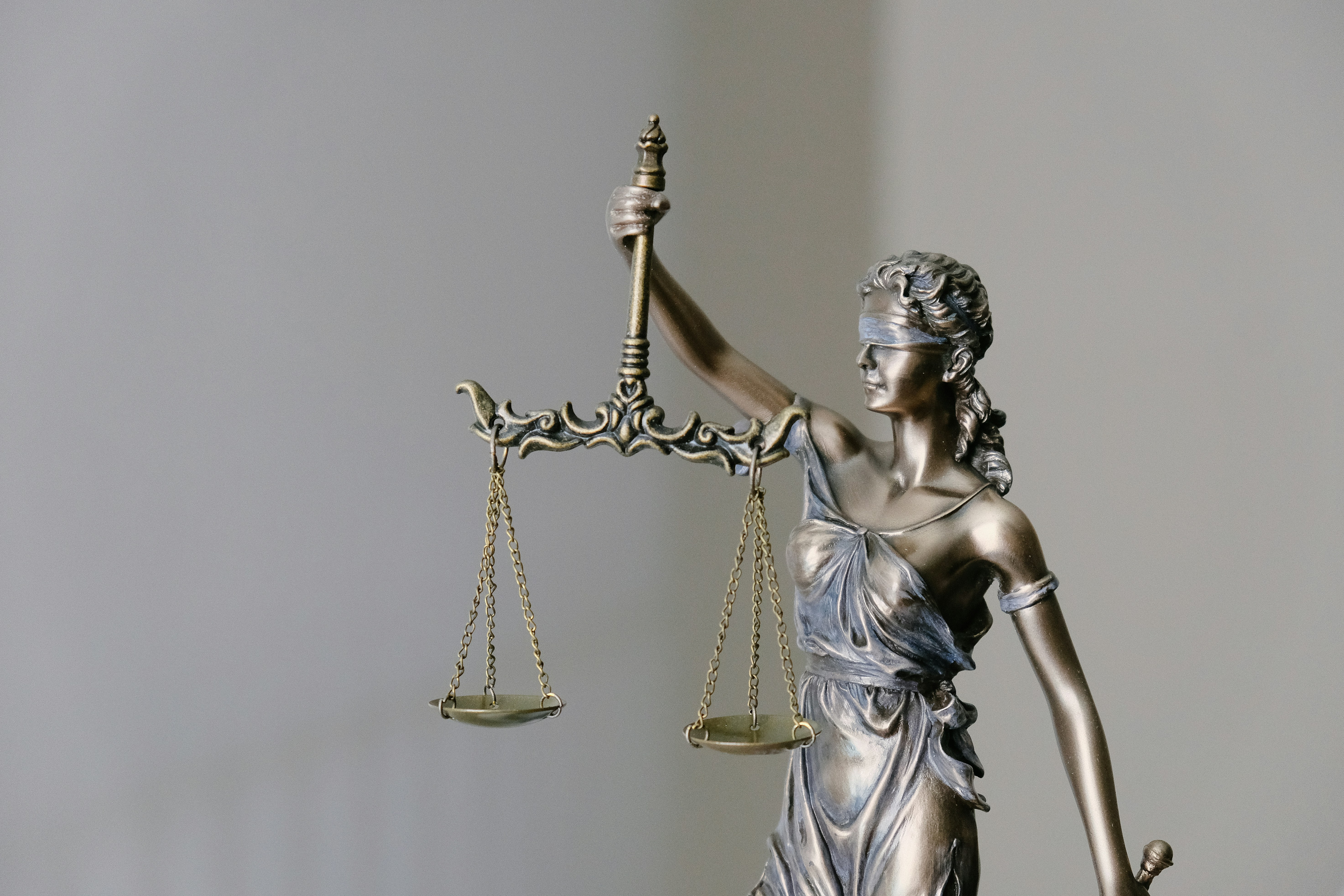 bronze statue of lady justice holding the scales of justice