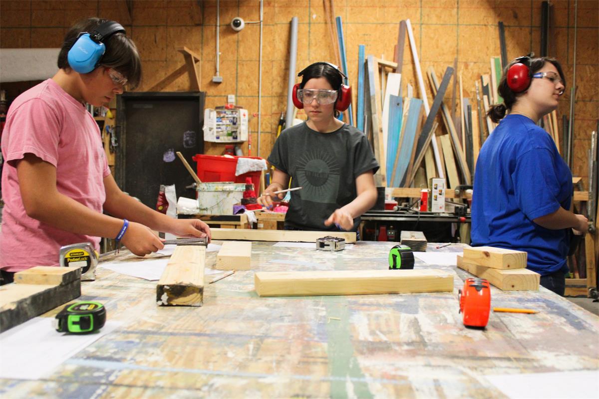 Three students engaged in a tech theatre workshop
