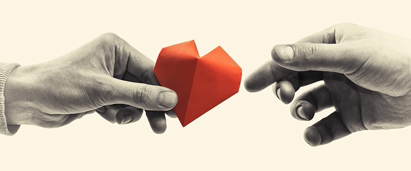 hand passing paper heart