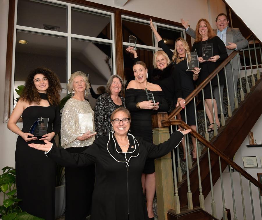 Award winners posing with trophies on a staircase at the annual gala