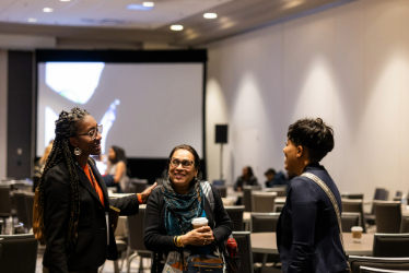 Three women engaged in conversation at an event.
