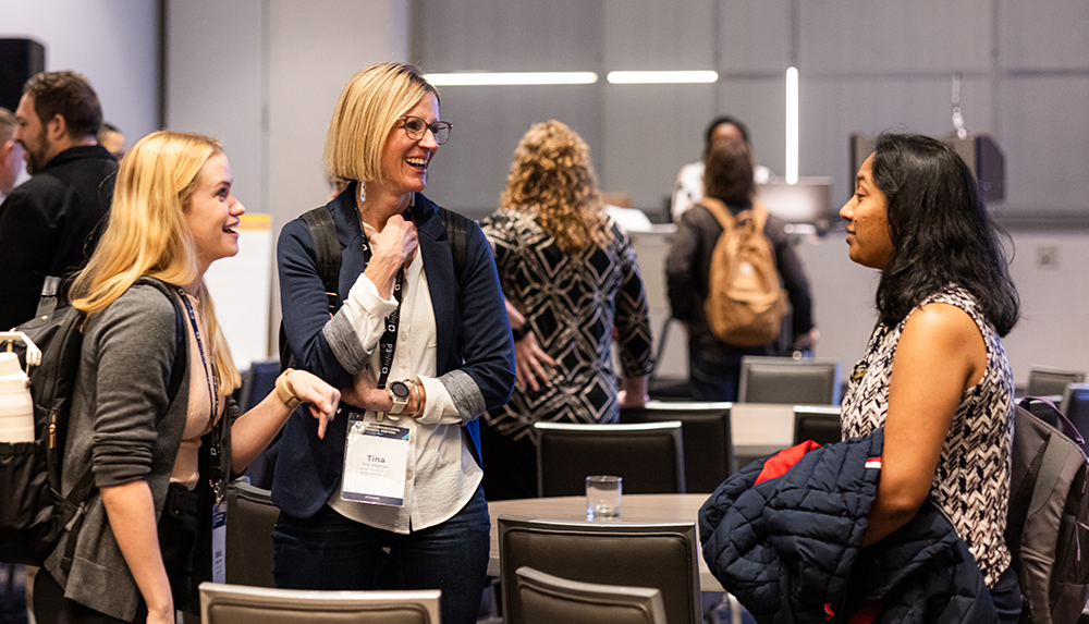 Three women engaged in conversation at an event.