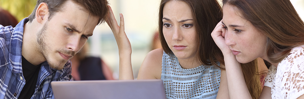 Friends using a laptop looking disappointed at the screen 
