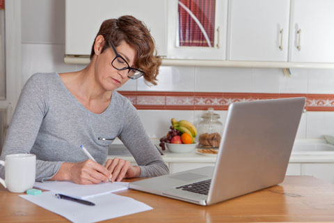 Worker at a desk with laptop and pen in hand