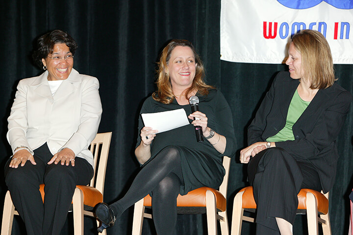 Kathy Francis and Val Ackerman (holding a microphone) share a laugh with Lee Ann Daly on stage