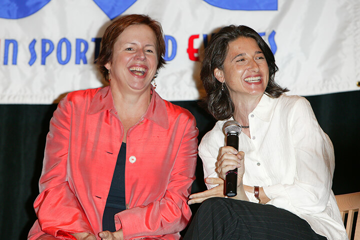Liz Dolan and Lydia Stephans (holding a microphone) laughing