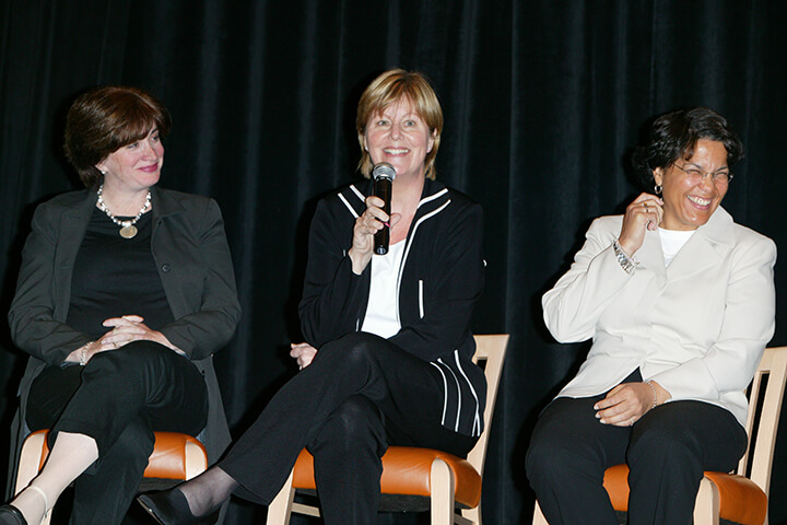 LeslieAnne Wade and Kathy Francis are amused by Stephanie Tolleson (holding a microphone) on stage during a talk