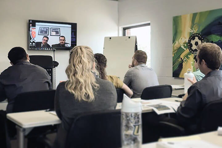 MLS Training Session with participants sitting in a classroom watching an educational video on the television