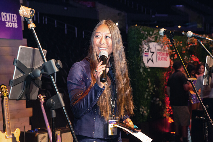 Michele Kajiwara speaking on stage at the Staples Center