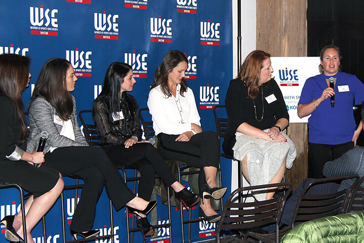 Group of ladies sitting down during a sponsorship panel talk while the woman on the far left is speaking while standing