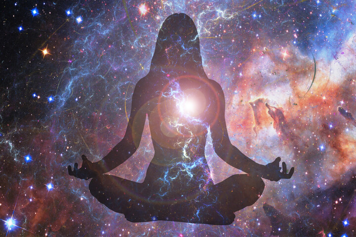 Silhouette of a person meditating with a galaxy themed background