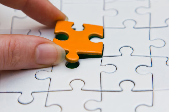 A person placing the final puzzle piece, and completing the puzzle