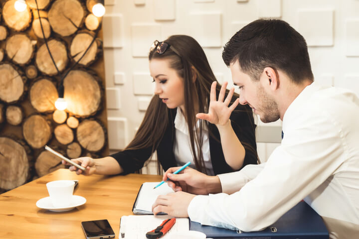 A woman on their phone not paying attention to the work being described by male co-worker