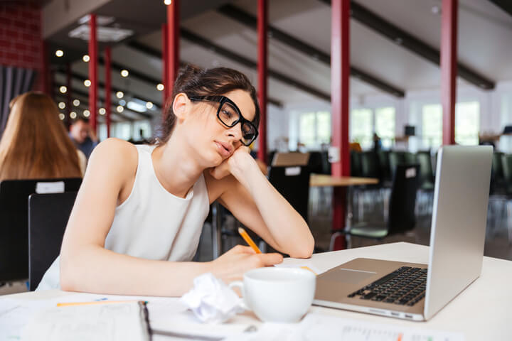 A women resting her head on her hand looking at her computer screen 