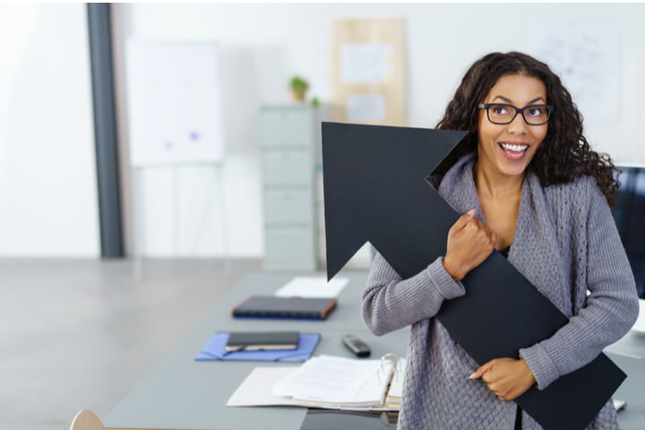 A woman holding a large arrow point upwards