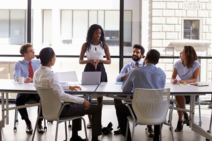 A woman standing up and giving a presentation to her colleagues