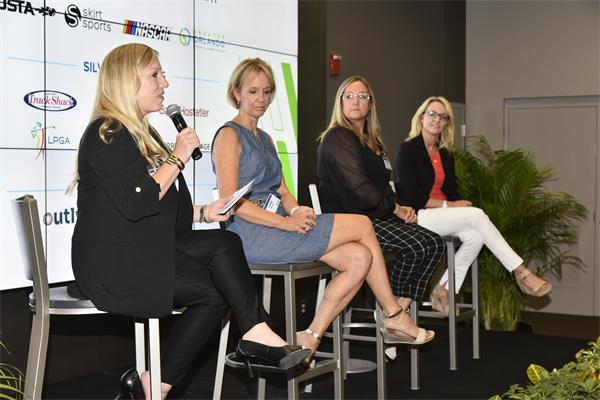 Four women sit on chairs on a stage during a panel discussion